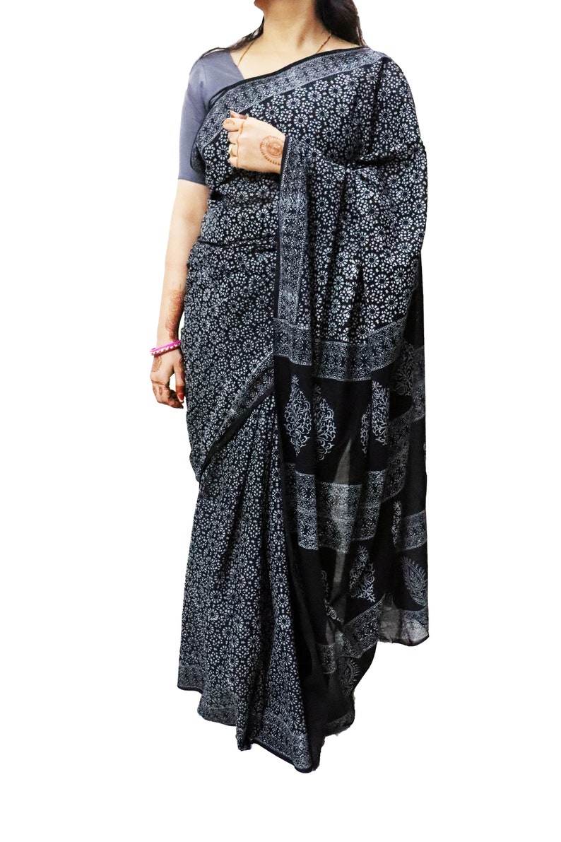 May include: A black and white cotton saree with a floral print. The saree has a border with a paisley design.