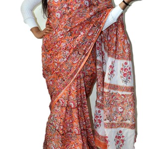 May include: A traditional Indian saree with a floral print in shades of orange, white, and red. The saree is draped around a person's body, showcasing the intricate design.