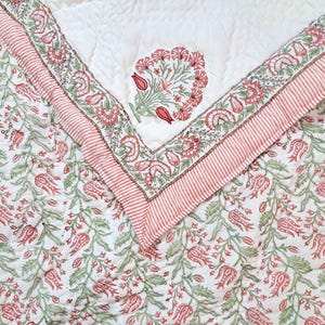 Twin size Jaipuri quilt folded to display hand block printed floral cotton fabric details