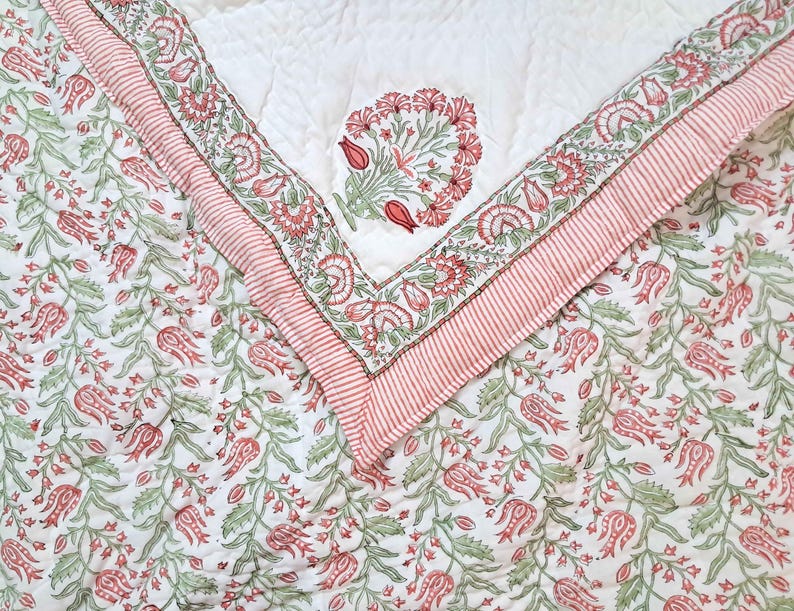 Twin size Jaipuri quilt folded to display hand block printed floral cotton fabric details