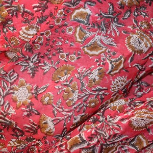 May include: Red fabric with a floral print in brown and white. The fabric has a textured, slightly wrinkled appearance.