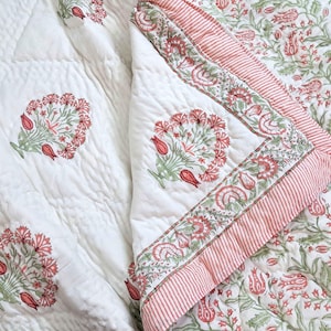 Handmade blush pink and green floral block print cotton quilt styled on cottage core bedroom bed