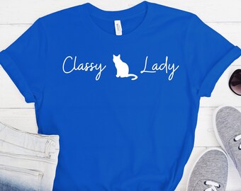 Peut inclure: Un t-shirt bleu royal avec une silhouette de chat blanche et le texte "Classy Lady" en blanc.