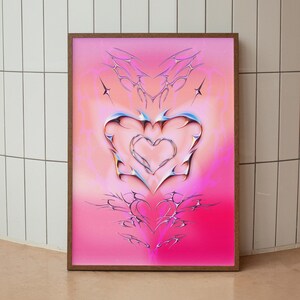May include: A framed print featuring a pink and orange gradient background. A large, silver heart with a smaller heart inside is the central focus of the image. Smaller hearts are scattered around the larger heart.