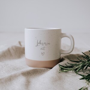 Elegante Tasse für Lehrerinnen, verziert mit einem herzlichen „Lehrerin mit Herz“-Schriftzug. Perfekt als Geschenk, um Dankbarkeit und Wertschätzung auszudrücken. Der dezente, zweifarbige Stil und das liebevolle Design machen sie zum idealen Begleiter für gemütliche Pausen. Ein emotionales Highlight, das jedem Schreibtisch Charme verleiht.