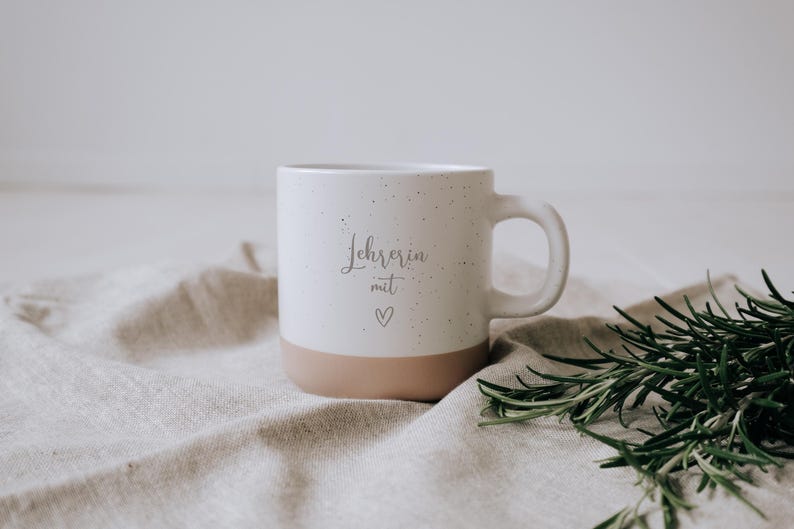 Elegante Tasse für Lehrerinnen, verziert mit einem herzlichen „Lehrerin mit Herz“-Schriftzug. Perfekt als Geschenk, um Dankbarkeit und Wertschätzung auszudrücken. Der dezente, zweifarbige Stil und das liebevolle Design machen sie zum idealen Begleiter für gemütliche Pausen. Ein emotionales Highlight, das jedem Schreibtisch Charme verleiht.