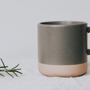 Eine stilvolle Keramiktasse in elegantem Schwarz und, ruht auf einem weichen Tuch. Perfekt für gemütliche Momente und eine liebevolle Geschenkidee. Bringen Sie Wärme und Stil in Ihre Kaffeepause mit diesen einzigartigen Tassen. Ideal für besondere Anlässe und alltäglichen Genuss.