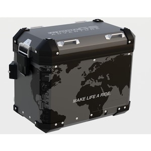 May include: A rectangular motorcycle top case in dark gray and black with reinforced corners. The side features a black world map graphic and the text "MAKE LIFE A RIDE." The lid displays "R1250GS ADVENTURE" branding with silver metal latches.