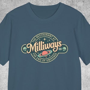 Könnte beinhalten: Ein dunkelblaues T-Shirt mit einem Retro-Logo, auf dem "The Restaurant at Milliways, The End of Universe" steht. Das Logo zeigt einen Planeten mit Ringen, Sternen und außerirdischen Gesichtern.