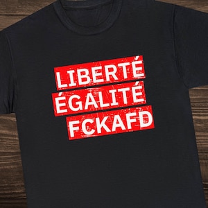 Może przedstawiać: Czarny T-shirt z czerwono-biało-niebieskim sloganem, który brzmi "LIBERTE EGALITE FCKAFD".