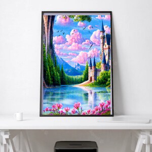 May include: A framed art print depicting a fairytale landscape. The artwork features a castle with tall spires, a serene lake, pink clouds, and vibrant green trees. Pink flowers line the water's edge, and the sky is a mix of blue and pink.