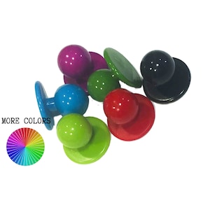 May include: Assortment of colourful plastic buttons with a flat back and a round top. The buttons are in various colours, including red, green, blue, black, and purple.  "MORE COLORS" is written in black text on a white background with a rainbow colour wheel below the text.