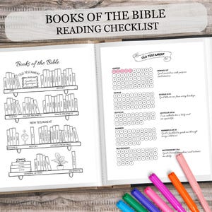 Puede incluir: Cuaderno abierto con una lista de verificación de lectura "Books of the Bible". La página izquierda presenta un diseño de estantería con títulos de libros. La página derecha tiene una lista de verificación con círculos. Se ven bolígrafos de colores.