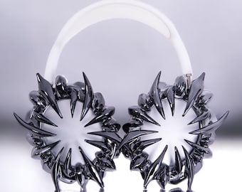 May include: A pair of white headphones with black, spiky, starburst-shaped earcups.