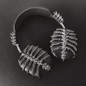 May include: Black headphones with a skeletal design on the earcups. The headphones have a black headband with a silver metal accent.