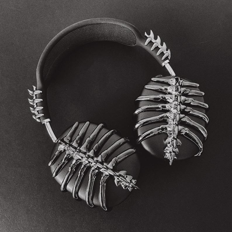 May include: Black headphones with a skeletal design on the earcups. The headphones have a black headband with a silver metal accent.