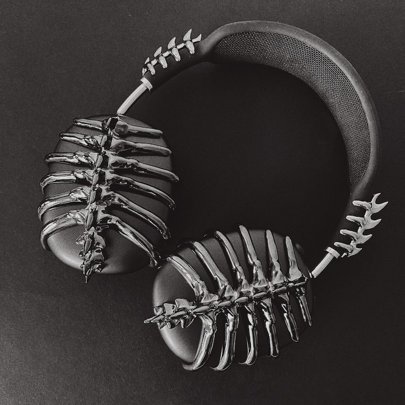 May include: Black headphones with a skeletal design on the earcups. The headphones have a black headband with a silver accent.