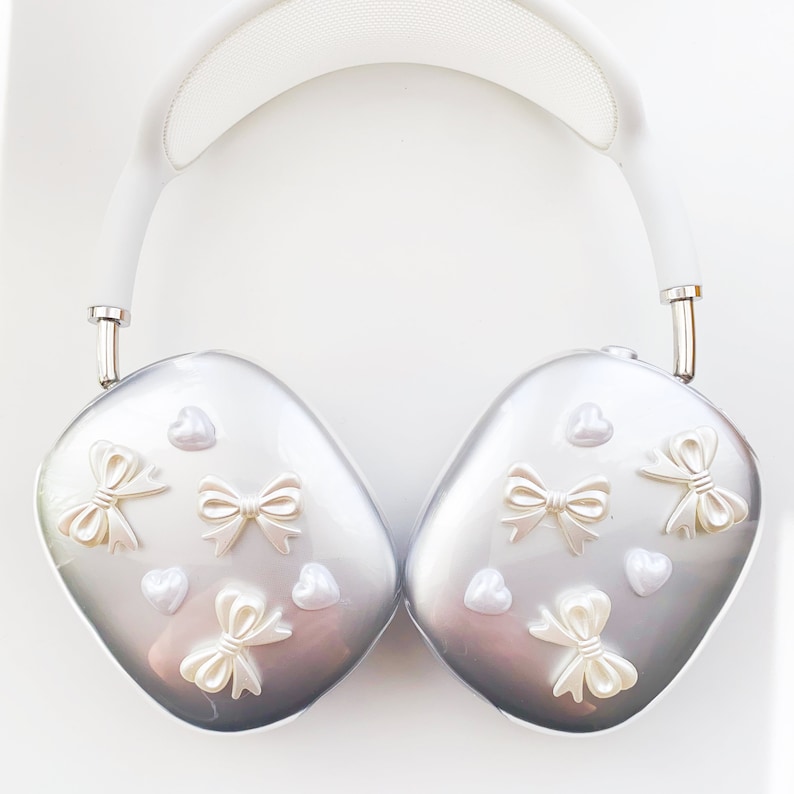 May include: Silver headphones with a white headband and white decorative bows and hearts on the earcups.