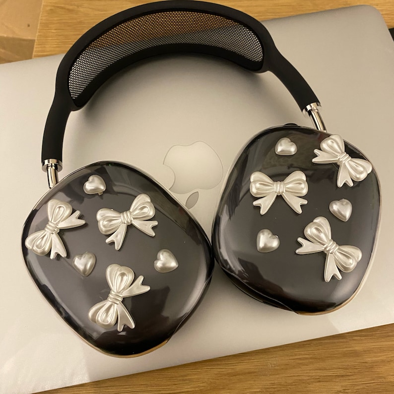 May include: Black headphones with a silver mesh headband and silver bow and heart embellishments on the earcups.