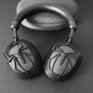 May include: Black wireless headphones with a spider-man design on the earcups. The headphones have the word "SONY" printed on the side.