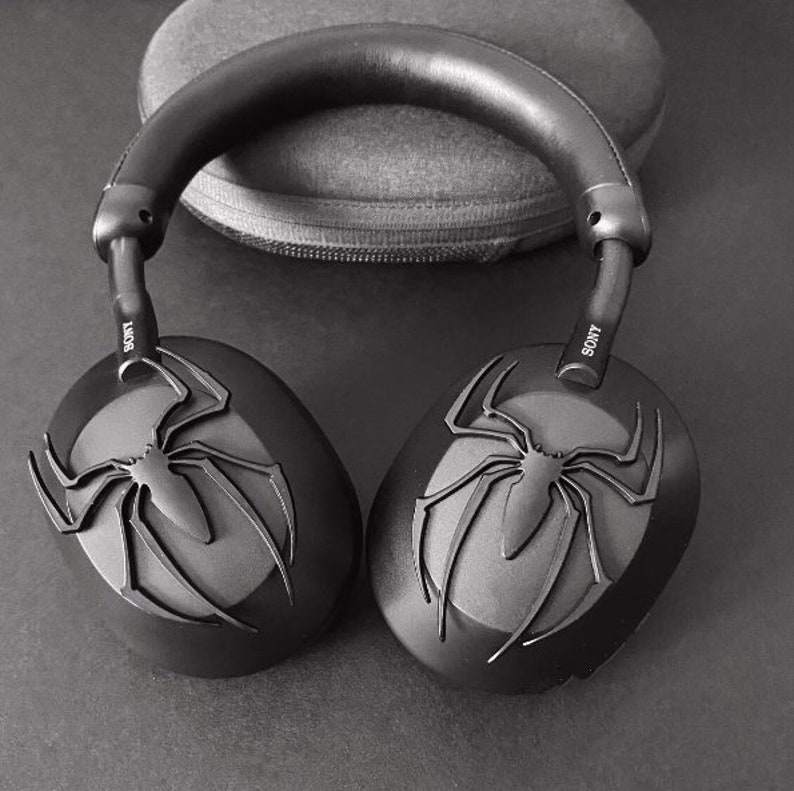 May include: Black wireless headphones with a spider-man design on the earcups. The headphones have the word "SONY" printed on the side.