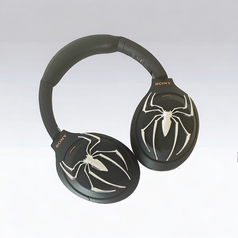 May include: Black over-ear headphones with a spider web design on each earcup. The headphones have the word "SONY" printed on each earcup.