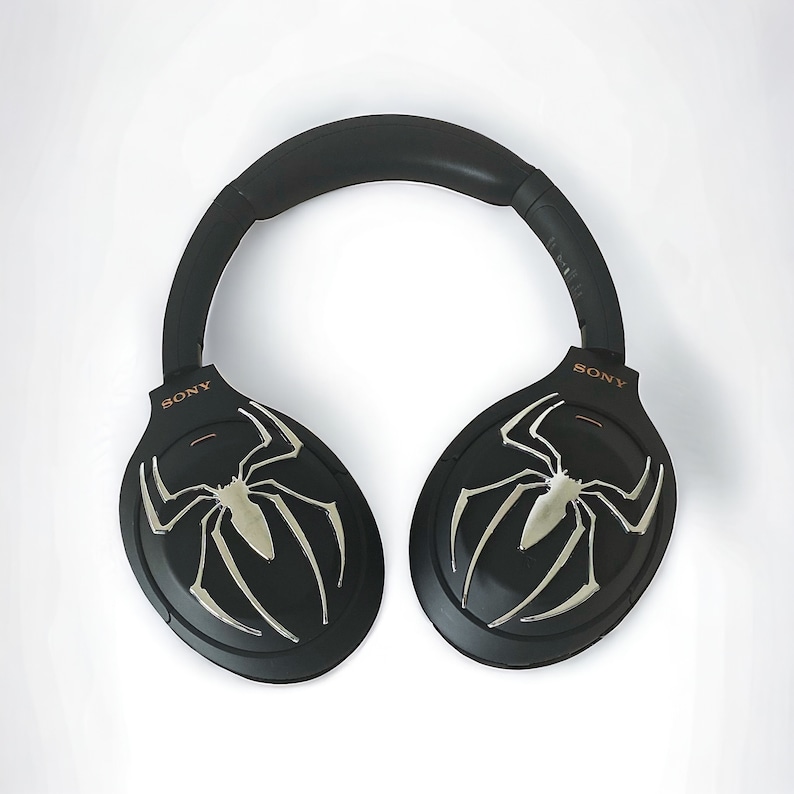 May include: Black over-ear headphones with a spider web design on each earcup. The headphones have the word "SONY" printed on each earcup.