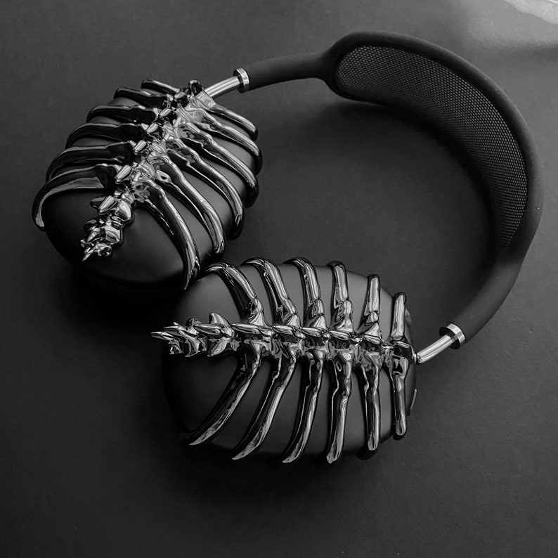 May include: Black headphones with a unique skeletal design. The headphones have a black headband and earcups with a silver skeletal pattern.
