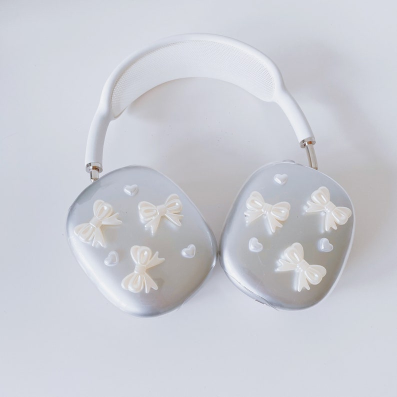 May include: White headphones with silver earcups decorated with white bows and hearts.