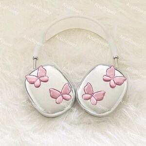 Peut inclure: Casque audio argent&eacute; avec un arceau blanc et des oreillettes orn&eacute;es de papillons roses. Ce casque, au design moderne, est probablement destin&eacute; &agrave; l'&eacute;coute de musique ou d'autres contenus audio.