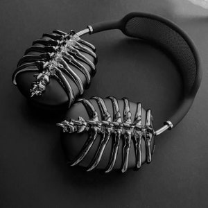 May include: Black headphones with a unique skeletal design. The headphones have a black headband and earcups with a silver skeletal pattern.