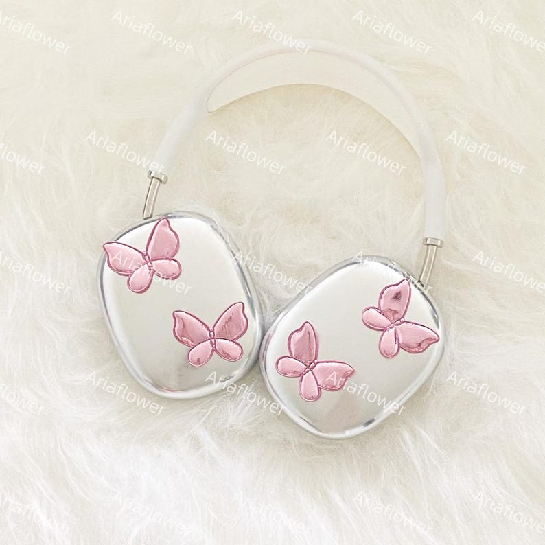 Peut inclure: Casque audio argent&eacute; orn&eacute; de papillons roses. Le casque poss&egrave;de un arceau blanc et des oreillettes avec trois papillons roses sur chaque &eacute;couteur. Le fond est une texture douce et blanche.