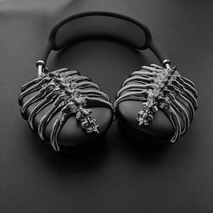 May include: Black headphones with a unique skeletal design on the earcups. The headphones have a black headband with a mesh pattern.