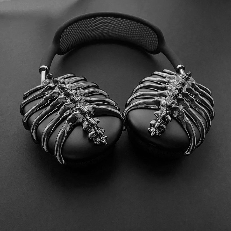May include: Black headphones with a unique skeletal design on the earcups. The headphones have a black headband with a mesh pattern.