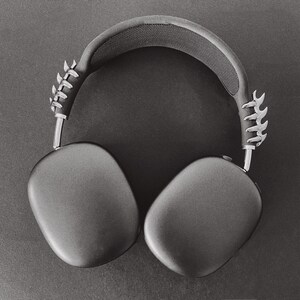 May include: Black over-ear headphones with a silver, textured, and slightly jagged design on the headband.
