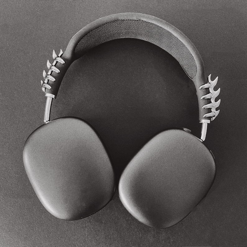 May include: Black over-ear headphones with a silver, textured, and slightly jagged design on the headband.