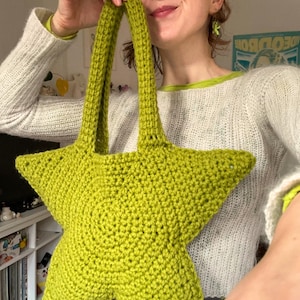 Könnte beinhalten: Eine limegrüne, gehäkelte Tasche in Sternform mit zwei Henkeln.