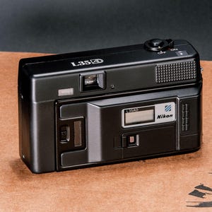 Back view of the Nikon L35AD (Pikaichi) film camera, showing the Quartz Date LCD screen and film door window.