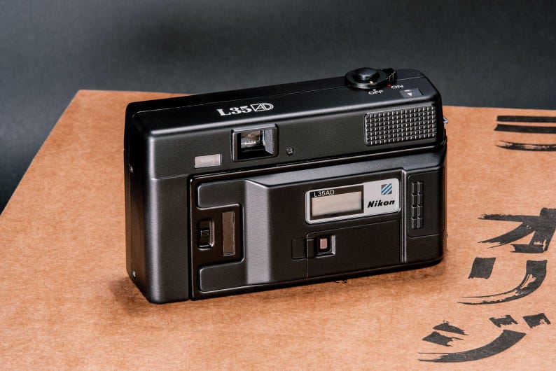 Back view of the Nikon L35AD (Pikaichi) film camera, showing the Quartz Date LCD screen and film door window.