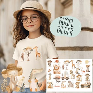 Könnte beinhalten: Ein junges Mädchen trägt ein weißes T-Shirt mit einem Safari-Tiermotiv, darunter eine Giraffe und ein Baum. Das Bild zeigt auch eine Sammlung von Safari-Bügelbildern mit verschiedenen Tieren und Landschaften. Der Text "BÜGEL BILDER" ist sichtbar.