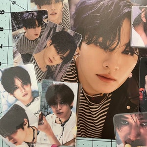 May include: A collection of photo cards featuring a young man with black hair. The cards are arranged in a grid pattern on a blue and white grid background. The cards show the man in different poses and outfits.