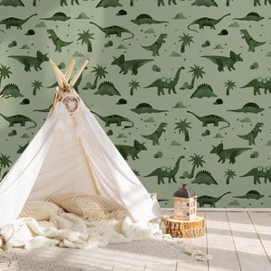 Op de afbeelding: Een groen-wit behang met een herhalend patroon van dinosaurussen, palmbomen en wolken. Op de voorgrond staat een witte tipi-tent met kussens en dekens erin.
