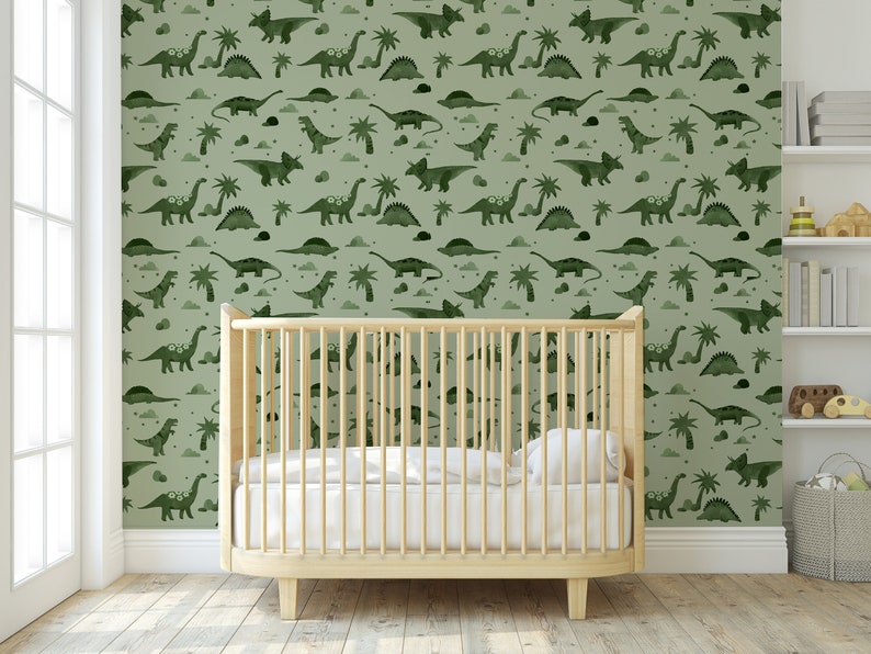 Op de afbeelding: Een babykamer met een wieg voor een muur met een groene dinosaurusbehang. Het behang heeft een herhalend patroon van dinosaurussen, palmbomen en wolken.