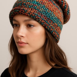 May include: A colorful, chunky knit beanie in shades of teal, orange, and rust. The hat has a folded brim and a relaxed fit. The beanie is made of a thick, textured yarn, perfect for cold weather.