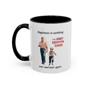 Op de afbeelding: Een witte keramische mok met een zwarte rand en handvat. De mok heeft een zwart-wit afbeelding van twee mannen die vissen met de tekst "Happiness is watching The Andy Griffith Show over and over again."
