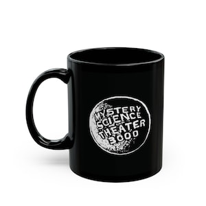 May include: Black ceramic coffee mug featuring the text "MYSTERY SCIENCE THEATER 3000" in white within a distressed circle. The mug has a curved handle and a glossy finish, perfect for enjoying your favorite beverage.