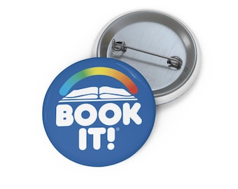 Könnte beinhalten: Ein blauer Knopf mit einem weißen Buch und einem Regenbogen darüber. Der Text "BOOK IT!" befindet sich unter dem Buch.