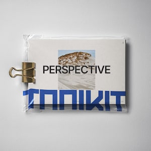 May include: A white card with the word "PERSPECTIVE" in black text and a photo of a sand dune. The card is in a clear plastic sleeve with a gold binder clip.