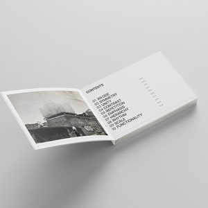 May include: An open book with a black and white photo on the left page and a list of design principles on the right page. The list includes: An Ode, Symmetry, Unity, Contrast, Repetition, Emphasis, Hierarchy, Rhythm, Scale, and Functionality.