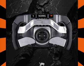 May include: A black and silver racing wheel with the name "NORRIS" displayed. The wheel has a central hub and multiple buttons and paddles. The background is black with an orange and black border.